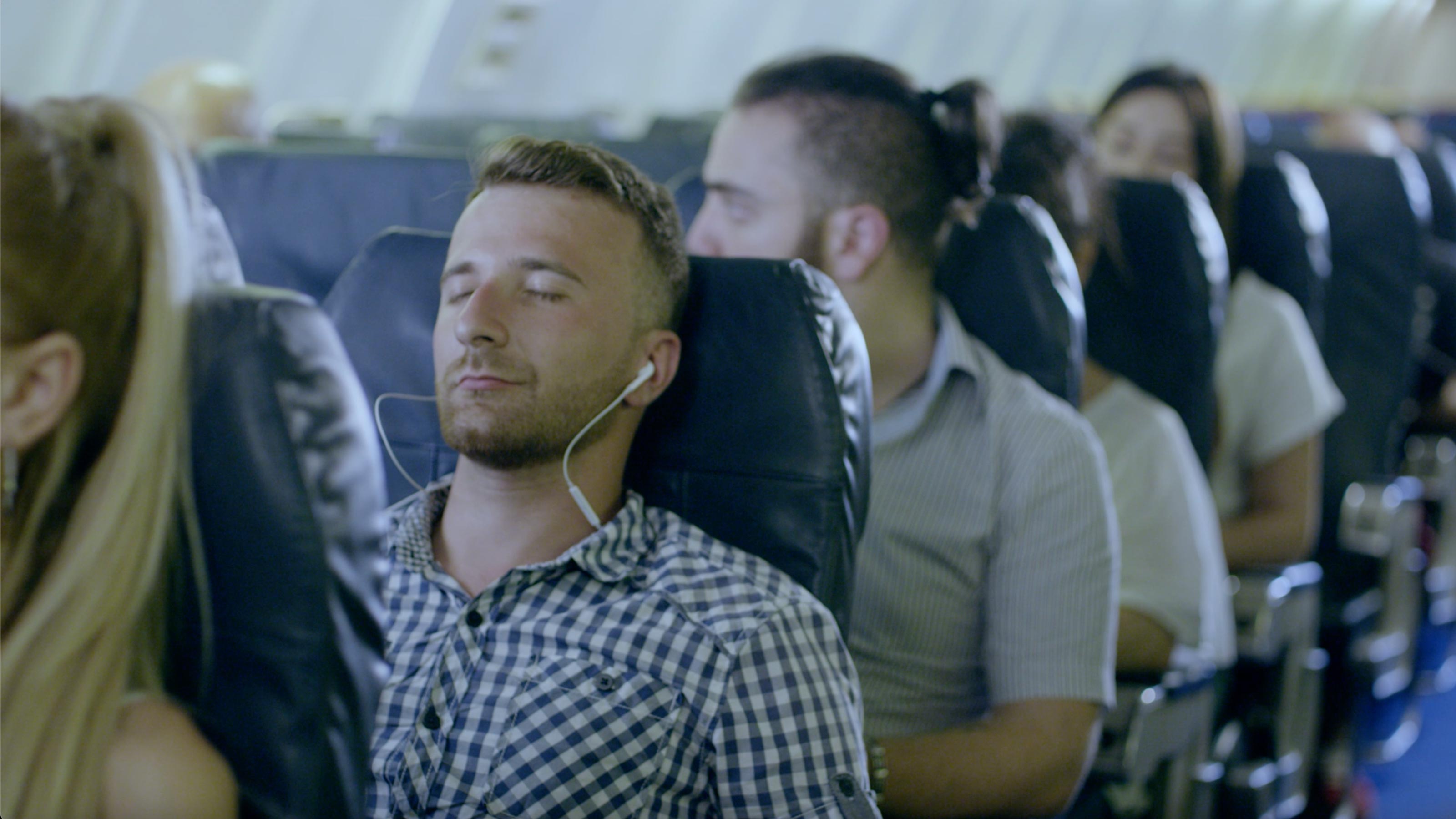 CalmFly App – Entspannt fliegen mit innerer Ruhe und Gelassenheit. Mann sitzt ruhig im Flugzeug mit Kopfhörern und hört beruhigende Audioübungen der CalmFly App.